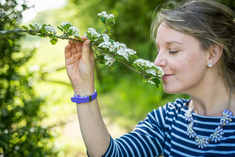 A woman closing her eyes and smelling white blossom